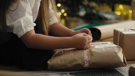 niña caucásica envolviendo regalos de navidad en el suelo.