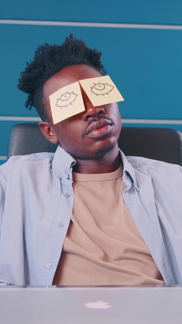 Creative guy with funny sticky notes on his eyes during a break in the office