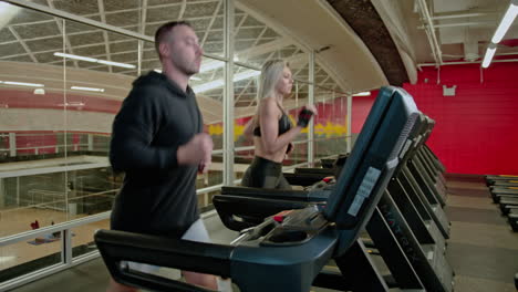 male and female couple exercising on treadmills, doing fitness exercise