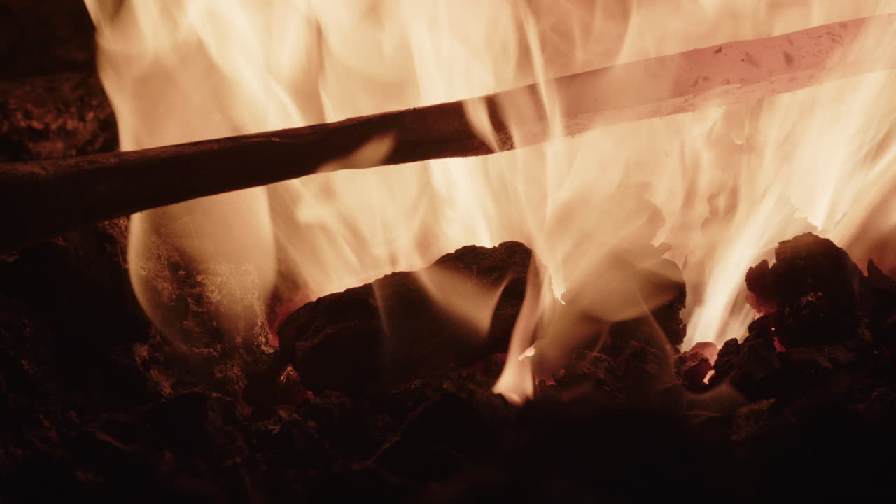 A red hot iron is inspected and returned to the fire for extra heating