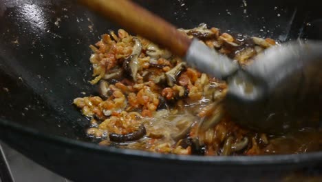 oil being added in to large wok for frying mushroom and shrimp concoction then mixed with spatula