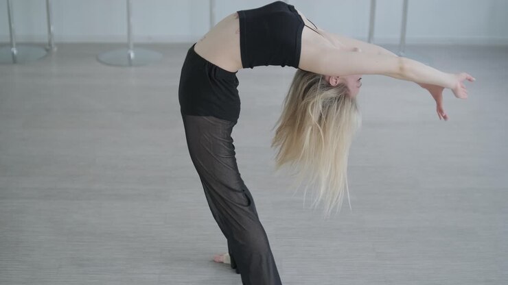 Ballerina in abiti neri che esegue danza contemporanea. Movimenti fluidi e aggraziati in una stanza bianca. Coreografia di balletto moderno.