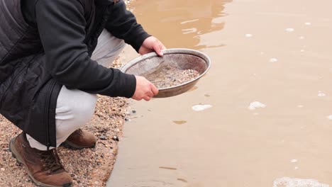 person panning for gold in muddy water