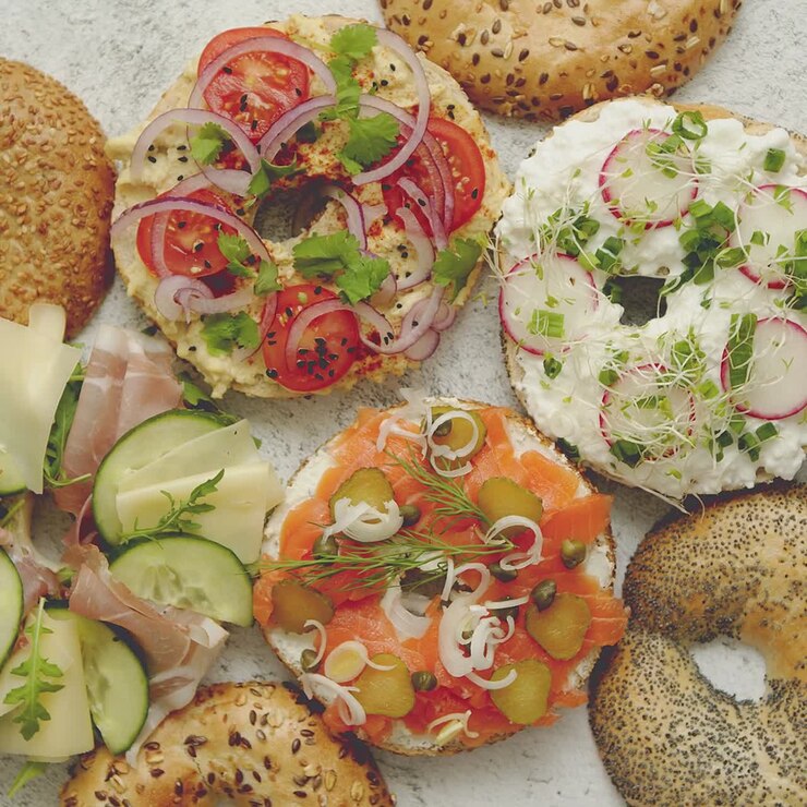 Panini bagel fatti in casa con diversi condimenti: salmone, formaggio cottage, hummus, prosciutto, ravanello