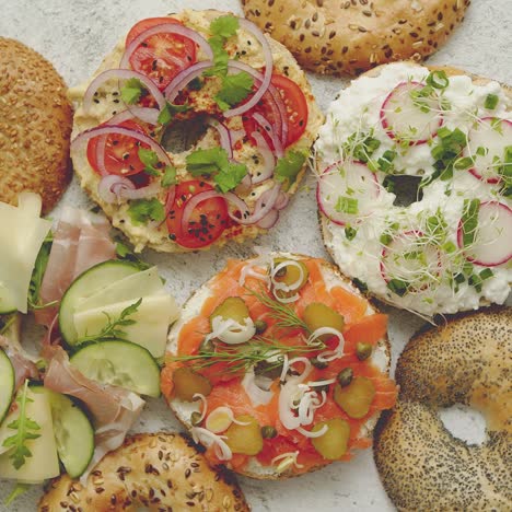 homemade bagel sandwiches with different toppings  salmon  cottage cheese  hummus  ham  radish