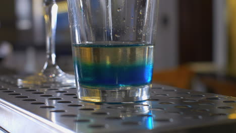 extreme close up of bar club cocktail preparation filling with blue drink a glass party nightlife concept