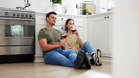 happy couple on floor in kitchen with red wine