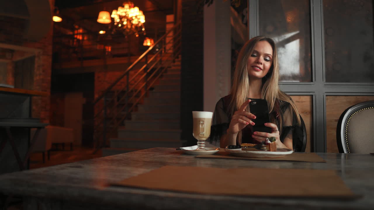 hermosa chica feliz emocional está haciendo una foto de la comida en la cafetería, café con leche en la mesa, postre helado pastel de chocolate menta cereza, comunicación en las redes sociales