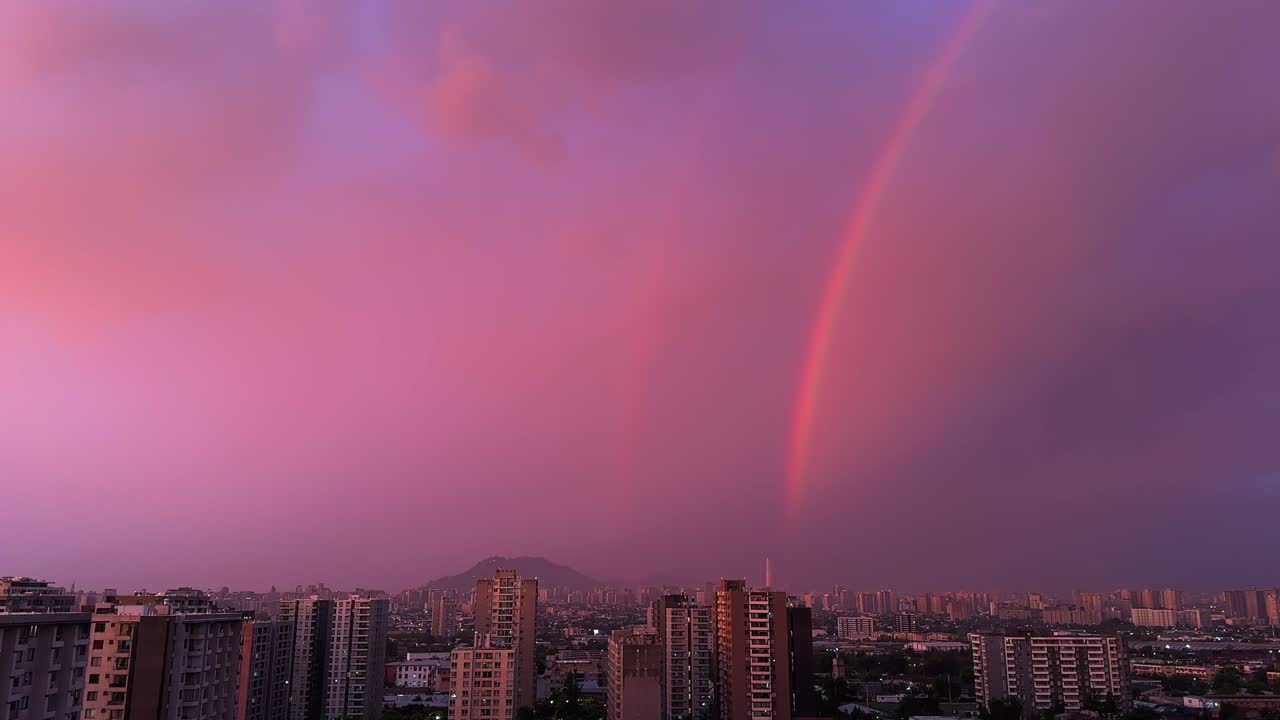 Arco-íris panorâmico ao pôr do sol sobre a cidade de Santiago com nuvens roxas.