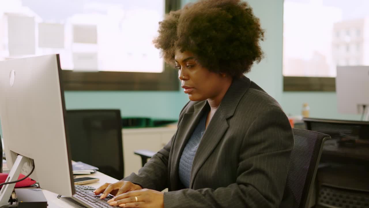 Concentrated afro woman working using computer in a coworking space