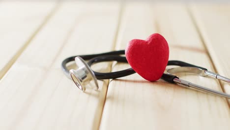 video de estetoscopio con corazón rojo en fondo de madera con espacio de copia