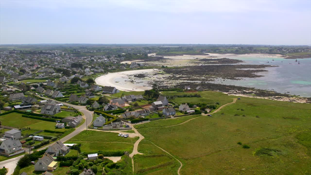 Coastal village near Brest, Brittany, featuring a sandy cove, rocky tidal zones, and lush green landscapes. This scenic capture highlights the charm of France’s Atlantic coastline. Drone aerial.