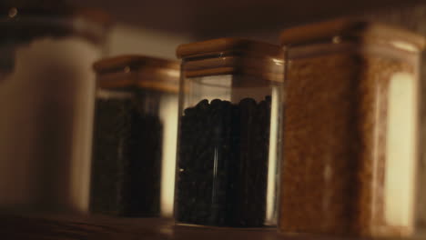 glass jars with wooden lids filled with spices on a warmly lit kitchen shelf