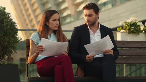 Business-people-looking-at-documents-on-street.-Coworkers-analyzing-graphics