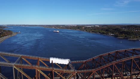 Genießen-Sie-Atemberaubende-Luftaufnahmen,-Während-Eine-Drohne-über-Den-Saint-Laurent-River-Fliegt,-An-Der-Quebec-Bridge-Vorbeifährt-Und-Im-Hintergrund-Ein-Frachtschiff-Einfängt