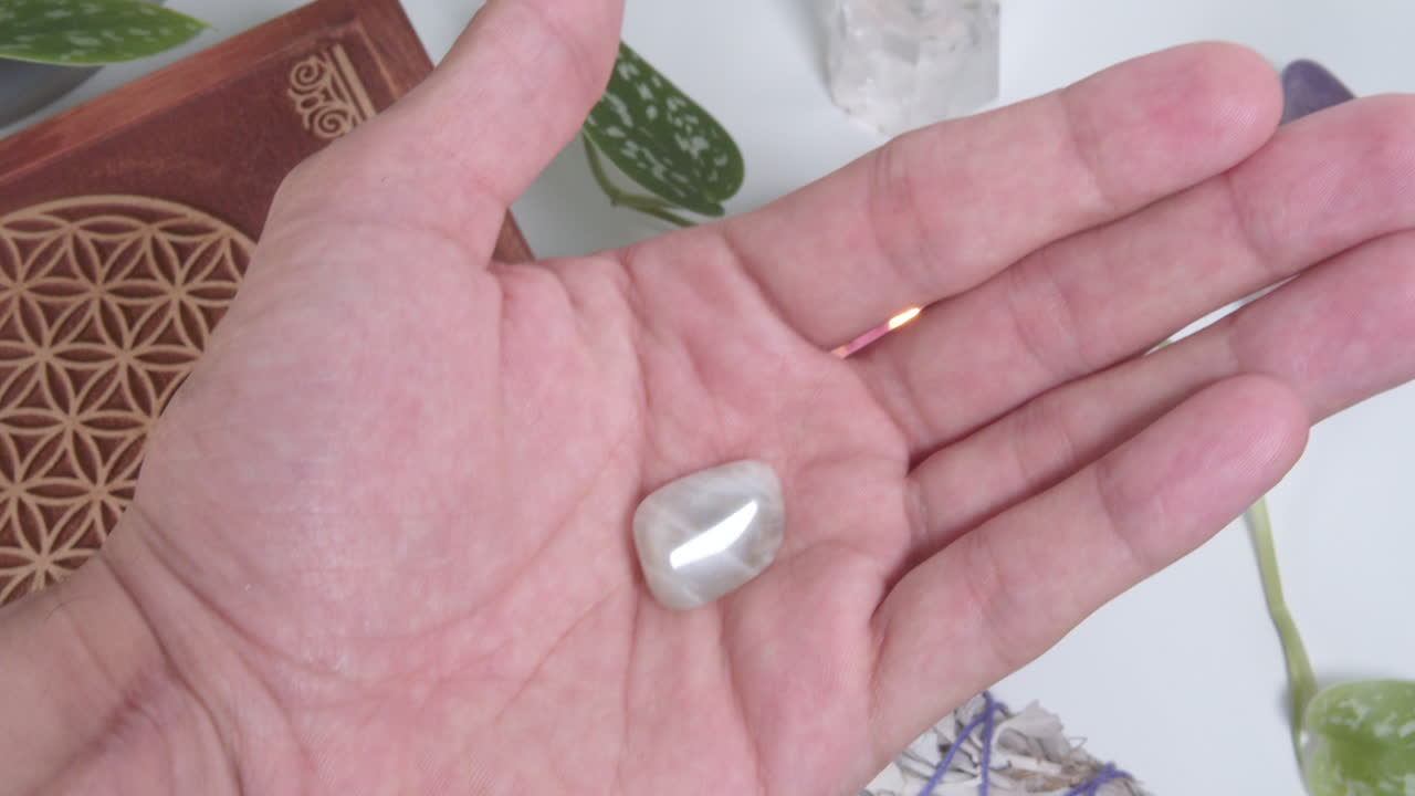 Small tumbled moonstone in the palm of a hand