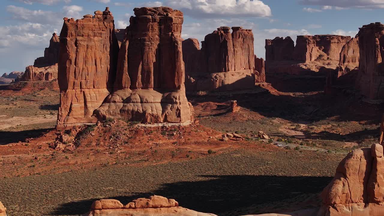 Imponenti formazioni rocciose rosse dominano il paesaggio aspro di Moab, Utah, una scena drammatica di bellezza naturale sullo sfondo di un deserto aperto e cieli sereni