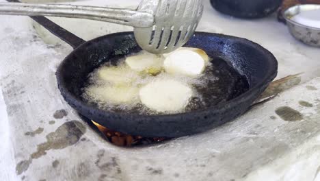 primer plano de una patata grande y redonda frita en aceite caliente, comida típica de la república dominicana