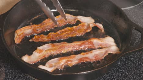 cast iron skillet on stove frying bacon