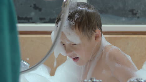 mother washing foam from child in the bath