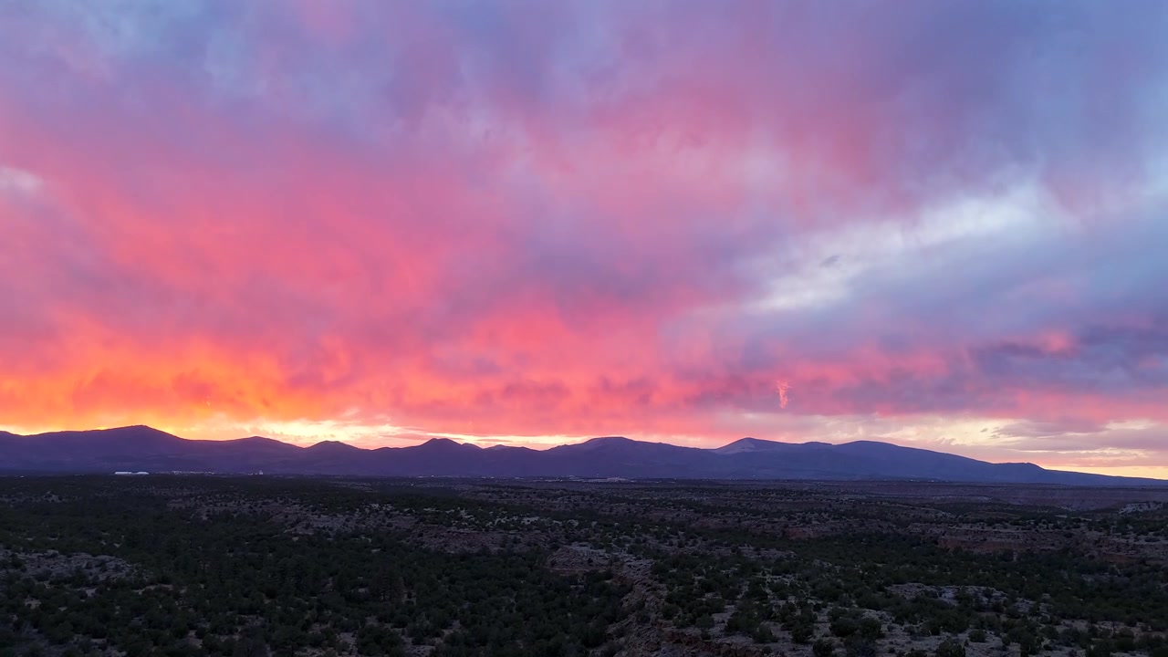 Un timelapse 4K con drone cattura un vivido flusso di colori del tramonto che si spostano tra nuvole drammatiche. Transizione atmosferica cinematografica con geografia desertica del sud-ovest ad alta quota e un bagliore radioso