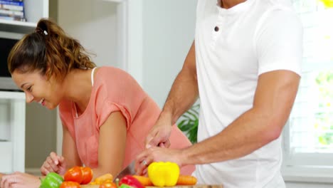 niña usando una tableta digital con su madre mientras el padre corta verduras en la cocina