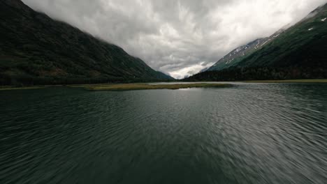 Fpv-luftdrohne,-Die-An-Bewölkten-Tag-über-Den-Alaska-see-Fliegt,-Umgeben-Von-Bergen-Und-üppiger-Flora