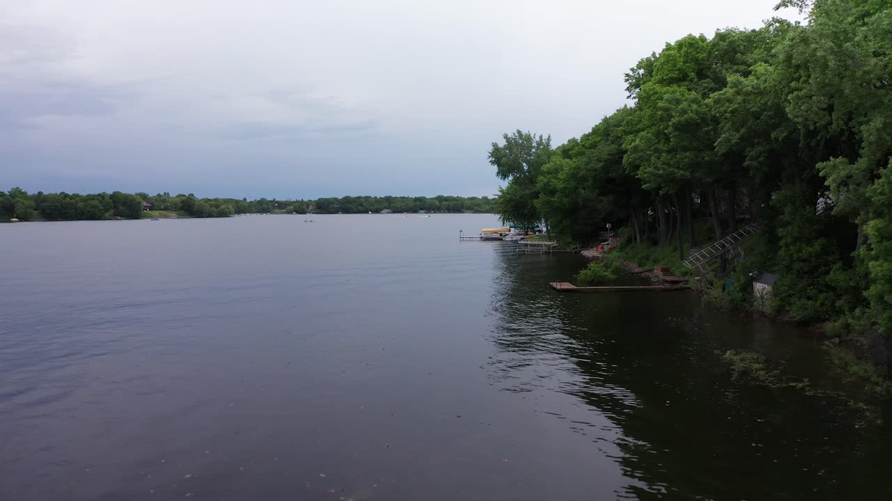 임박한 폭풍이 하늘과 물을 물들일 때 호숫가를 따라 낮은 공중 촬영