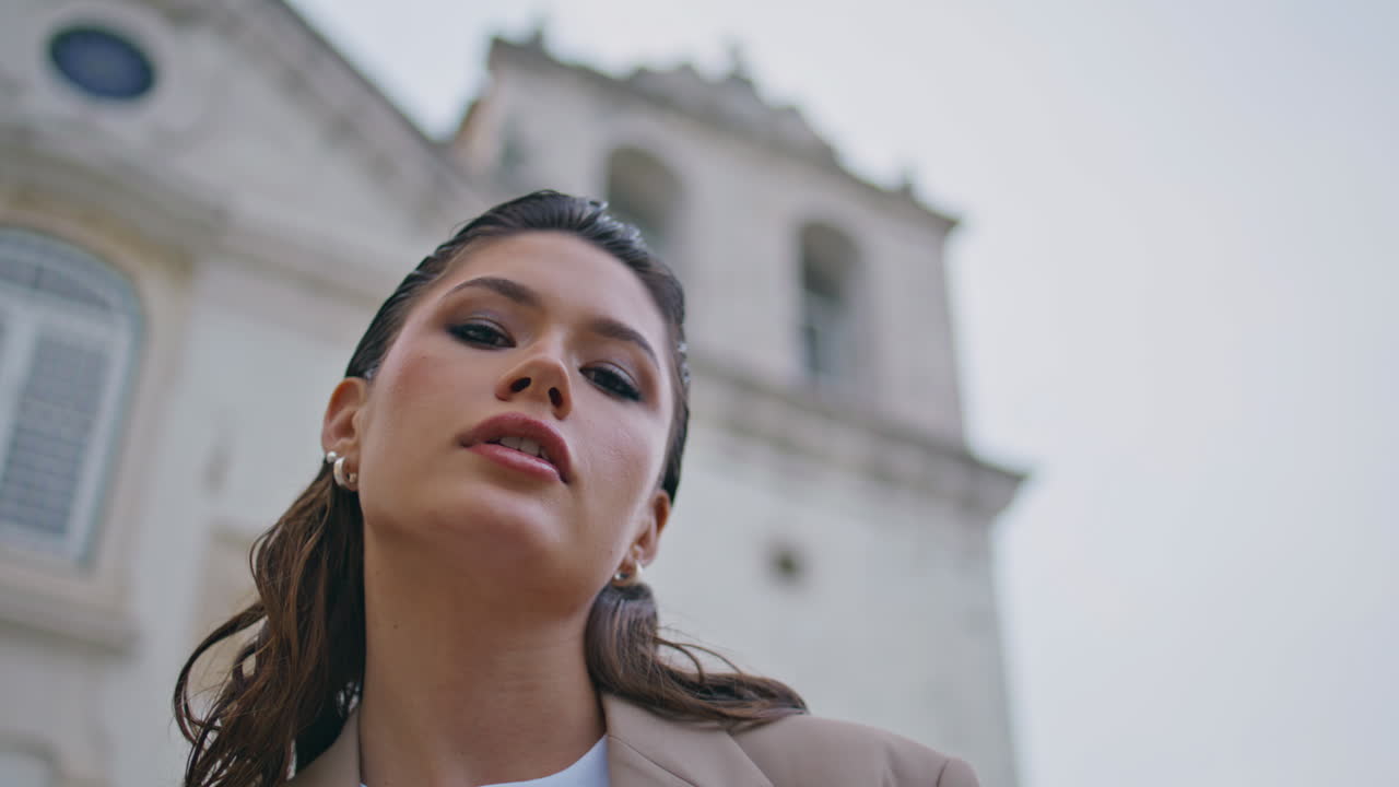closeup chica de moda mirando cámara en el cielo nublado de la ciudad. retrato de mujer posando