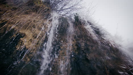 waterfall in winter, freezing water trickle cascade down at snowfall