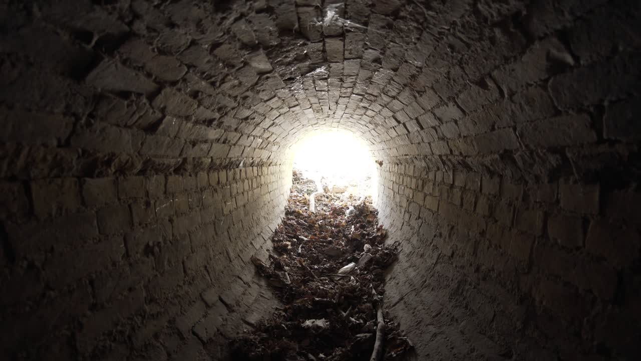 salida de viejo túnel de drenaje de ladrillo oval abandonado del siglo xix lleno de basura en el día.