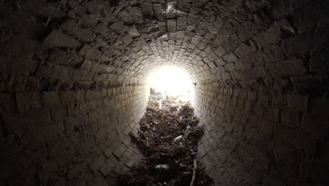 exit of old abandoned oval brick drainage tunnel of the 19th century littered with garbage in the day.