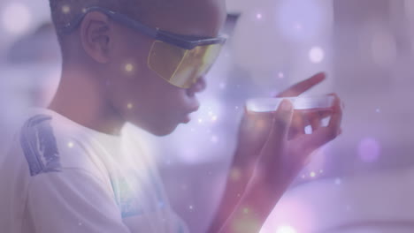 animación de partículas de luz sobre un escolar afroamericano estudiando la placa de petri en la clase de ciencias