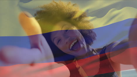 animación de la bandera colombiana ondeando sobre mujer biracial hablando video selfie a través de la cámara en la playa