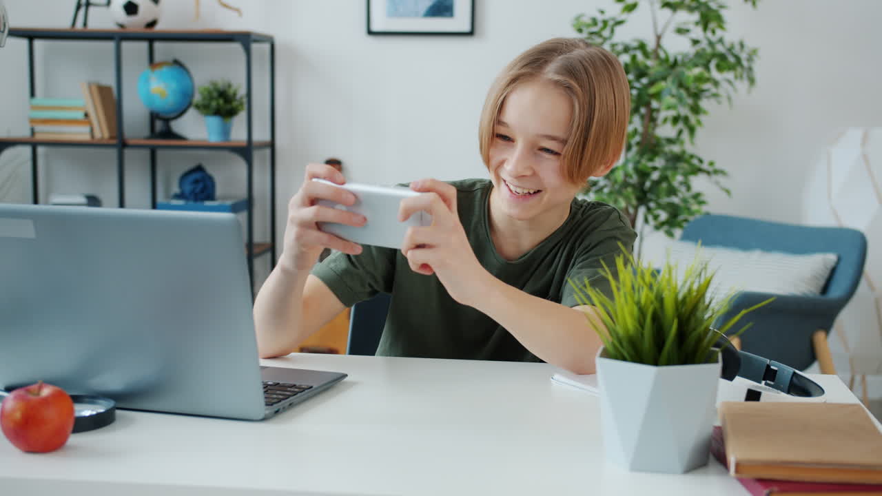 Adolescente che usa smartphone e laptop a casa