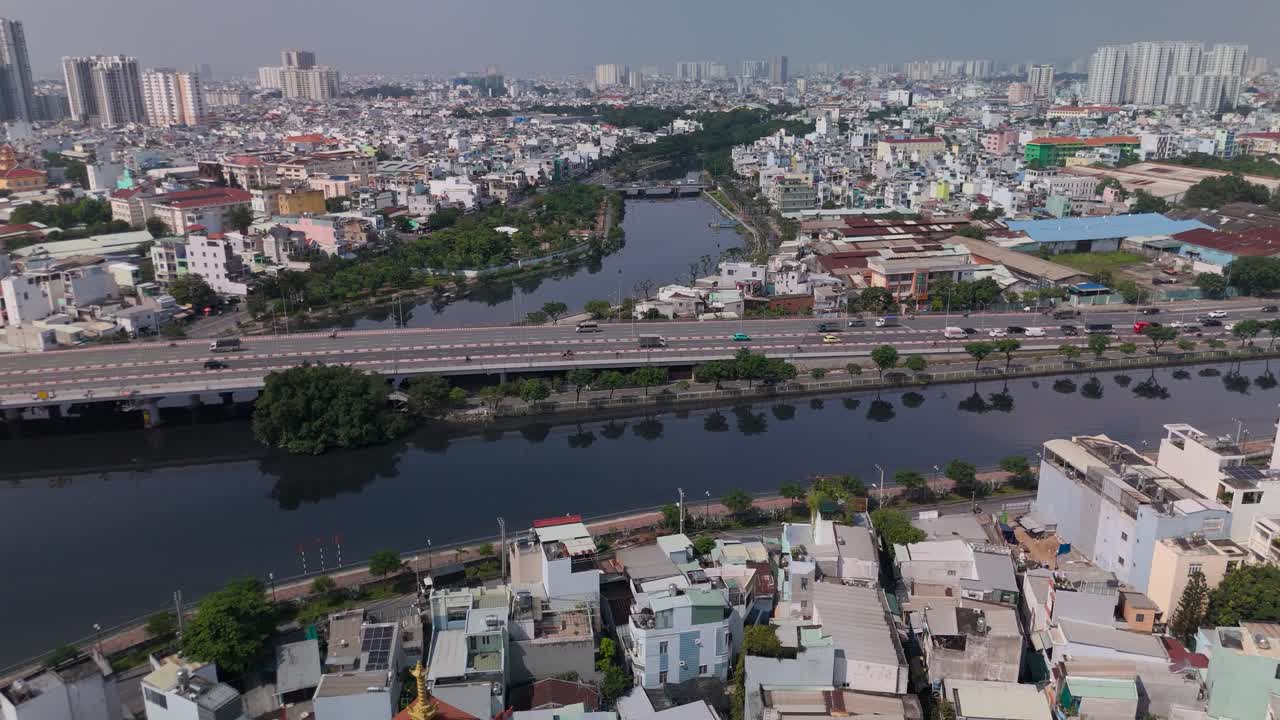 Aerial view of busy freeway over river with urban sprawl on sunny clear day