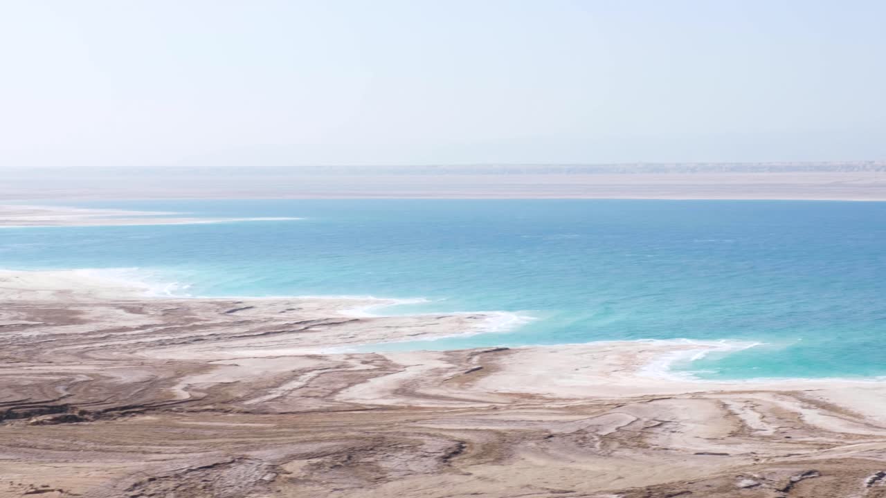 paisaje surrealista inusual del mar muerto en el valle del rift de jordania con agua turquesa y costa de arenas movedizas saladas, panorámica de izquierda a derecha del lago hipersalino
