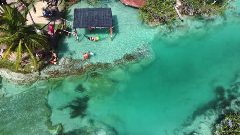 Aerial-shot-of-People-swimming-in-the-shallow-water-of-Bacalar-lake---Bacalar-,-Mexico