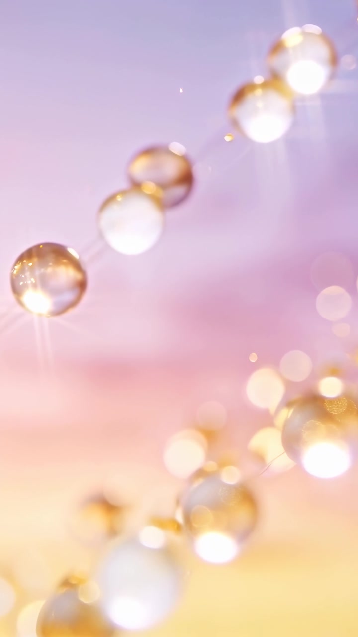 Video verticale: Fili di perline dorate che si muovono dopo uno spostamento della telecamera su un bokeh pastello, con goccioline.