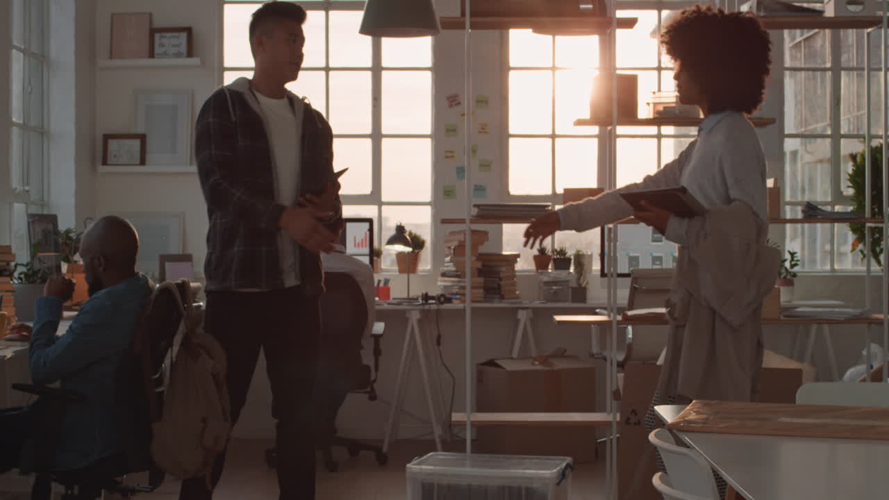 young asian businessman working late software developer meeting client shaking hands collaborating with intern on designing mobile application in office at sunset