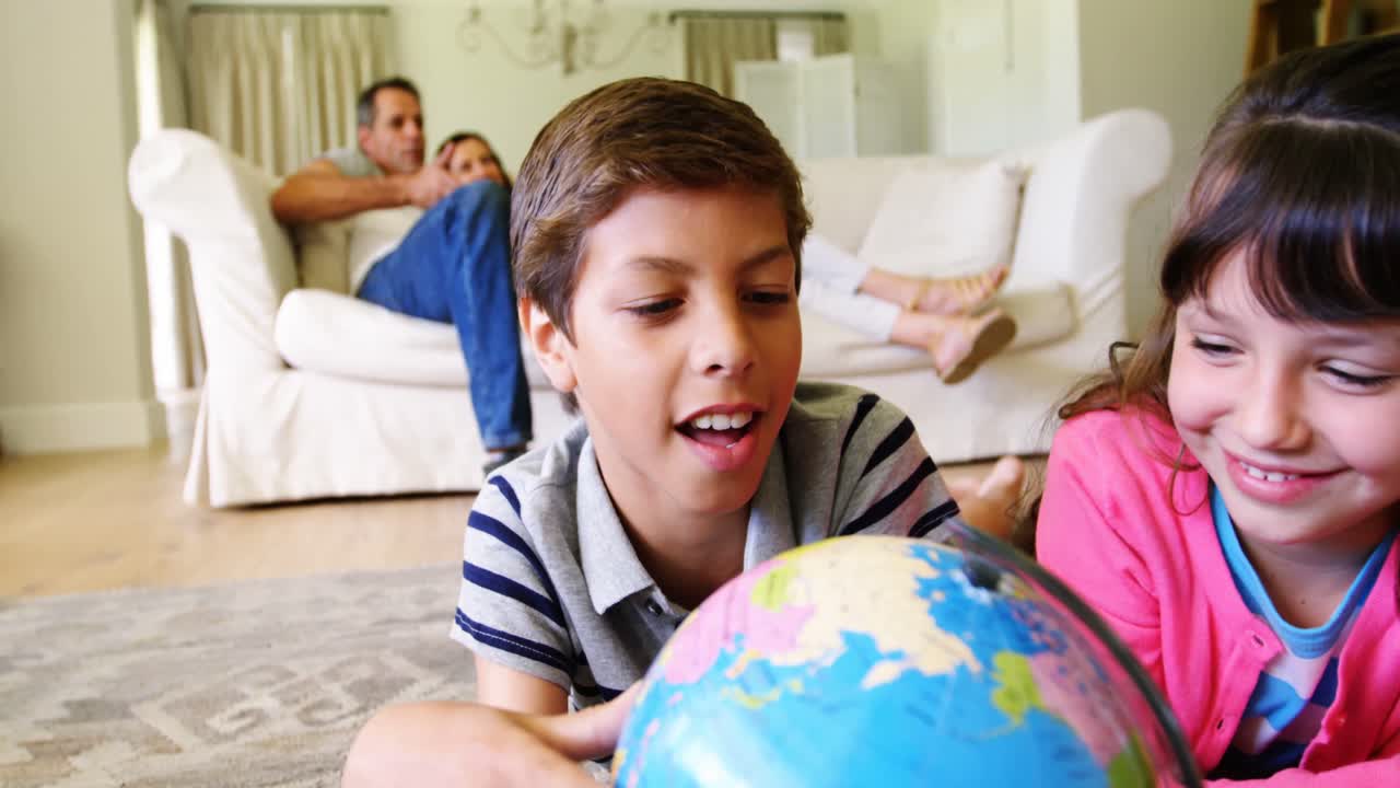 hermanos acostados y mirando el globo en la sala de estar