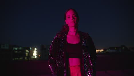 retrato de una mujer hermosa posando con los brazos cruzados por la noche buscando confianza con la luz roja en la ciudad