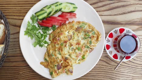 turkish breakfast with omelet, tea, and fresh vegetables