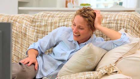 Curlyhaired-woman-laughing-in-front-of-her-tv