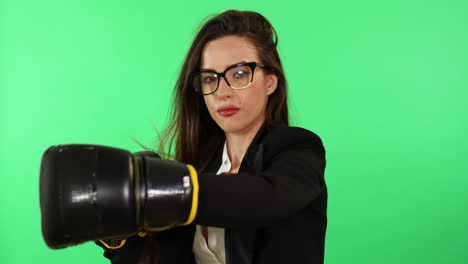 una joven morena sexy con gafas, camisa blanca y traje de negocios negro con guantes de boxeo y estrés punzante