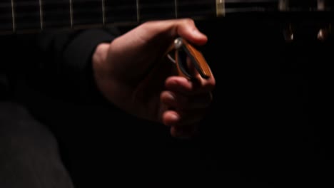 a man playing the guitar and putting a capo on