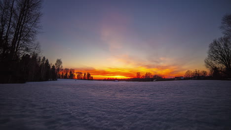 Panoramic-shot-of-golden-sunset-behind-snowy-winter-landscape-in-the-evening---time-lapse