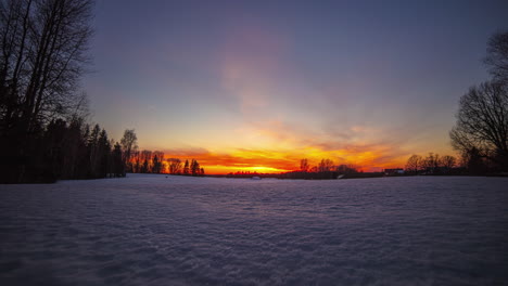 panoramic shot of golden sunset behind snowy winter landscape in the evening - time lapse