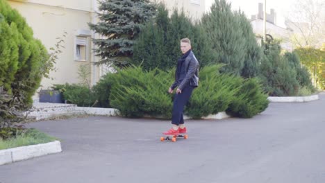 Cooler-Junger-Mann-In-Lederjacke,-Der-Auf-Seinem-Longboard-Skatet