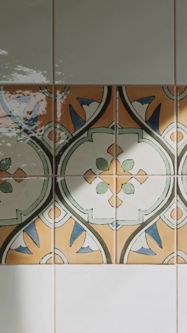Video verticale: Il sole si sposta su piastrelle decorative, proiettando bagliori di foglie e un'ombra obliqua in cucina.